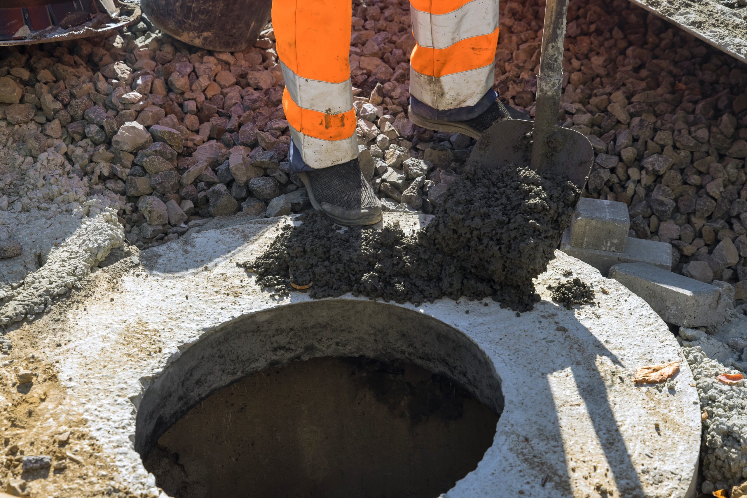 A worker the new road construction work on preparation for installation of sewer manholes hatches