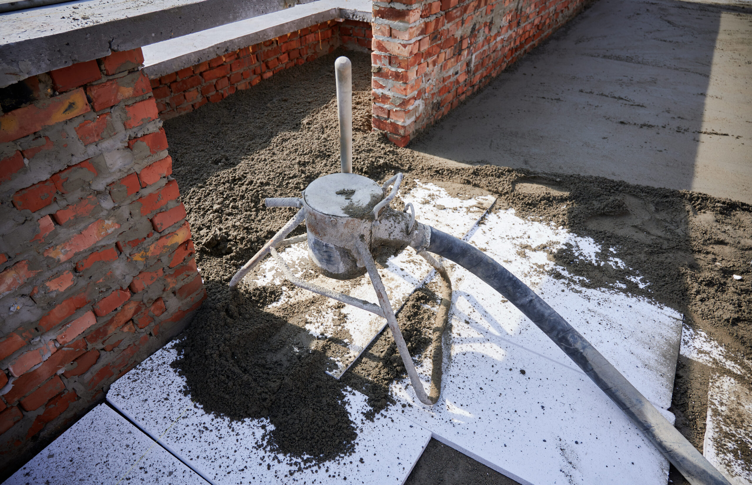 Building with concrete floor covered with sand-cement mix and professional equipment. Preparation of floor screed mixture with mortar mixer machine in new building at construction site.