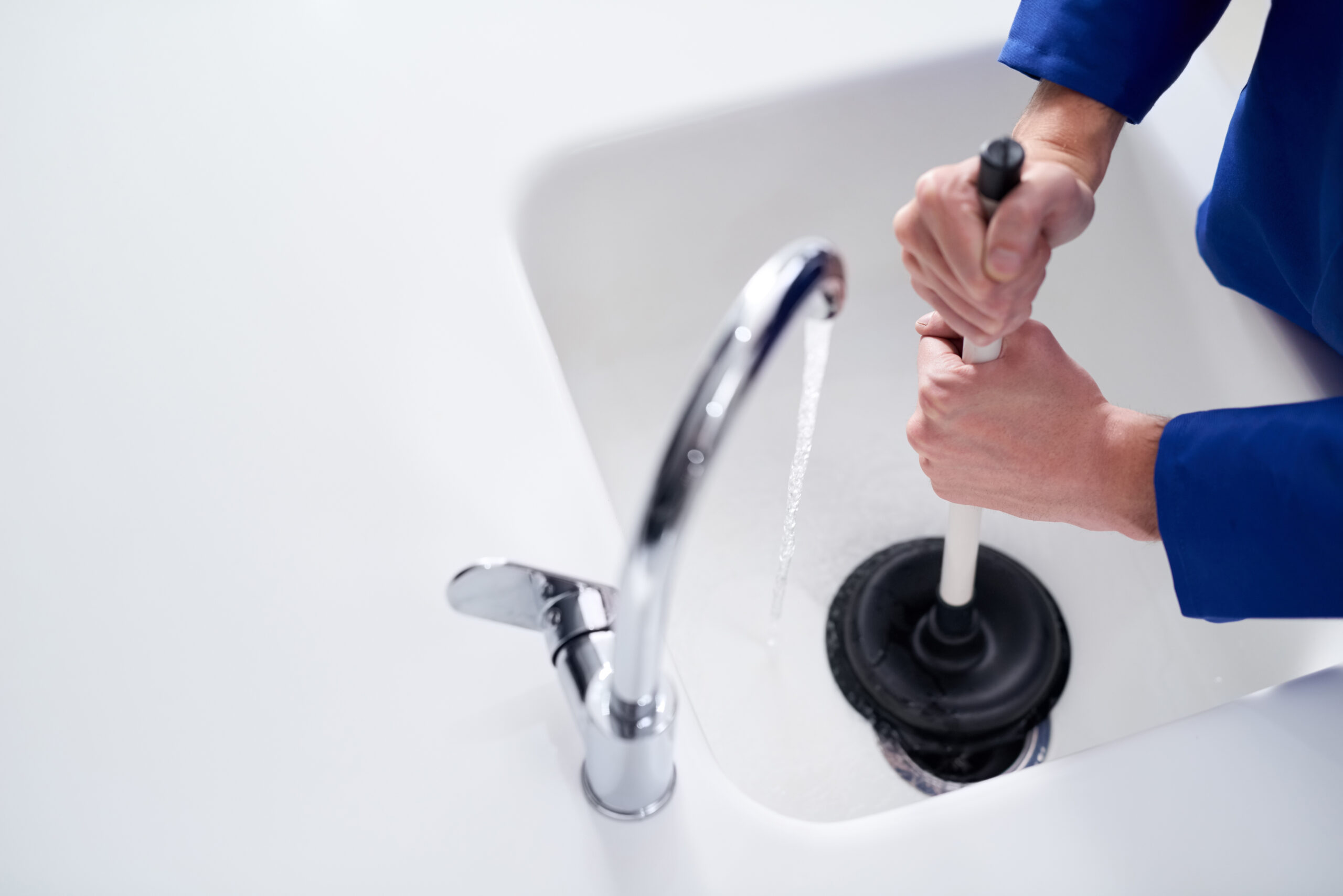 Keeping the drains clean. Cropped shot of a plumber	 unblocking a drain with a plunger