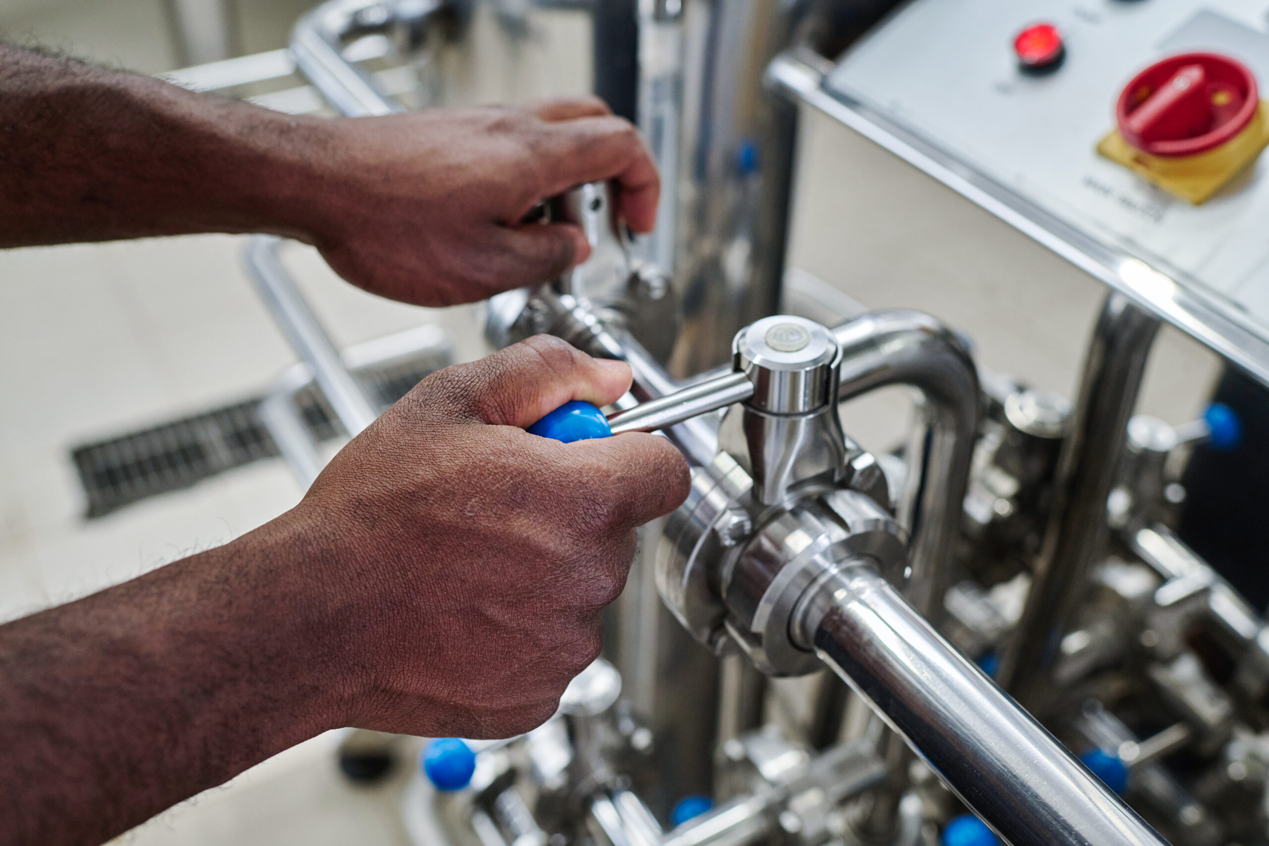 Close-up of African American worker turning levers on pipe to control the equipment