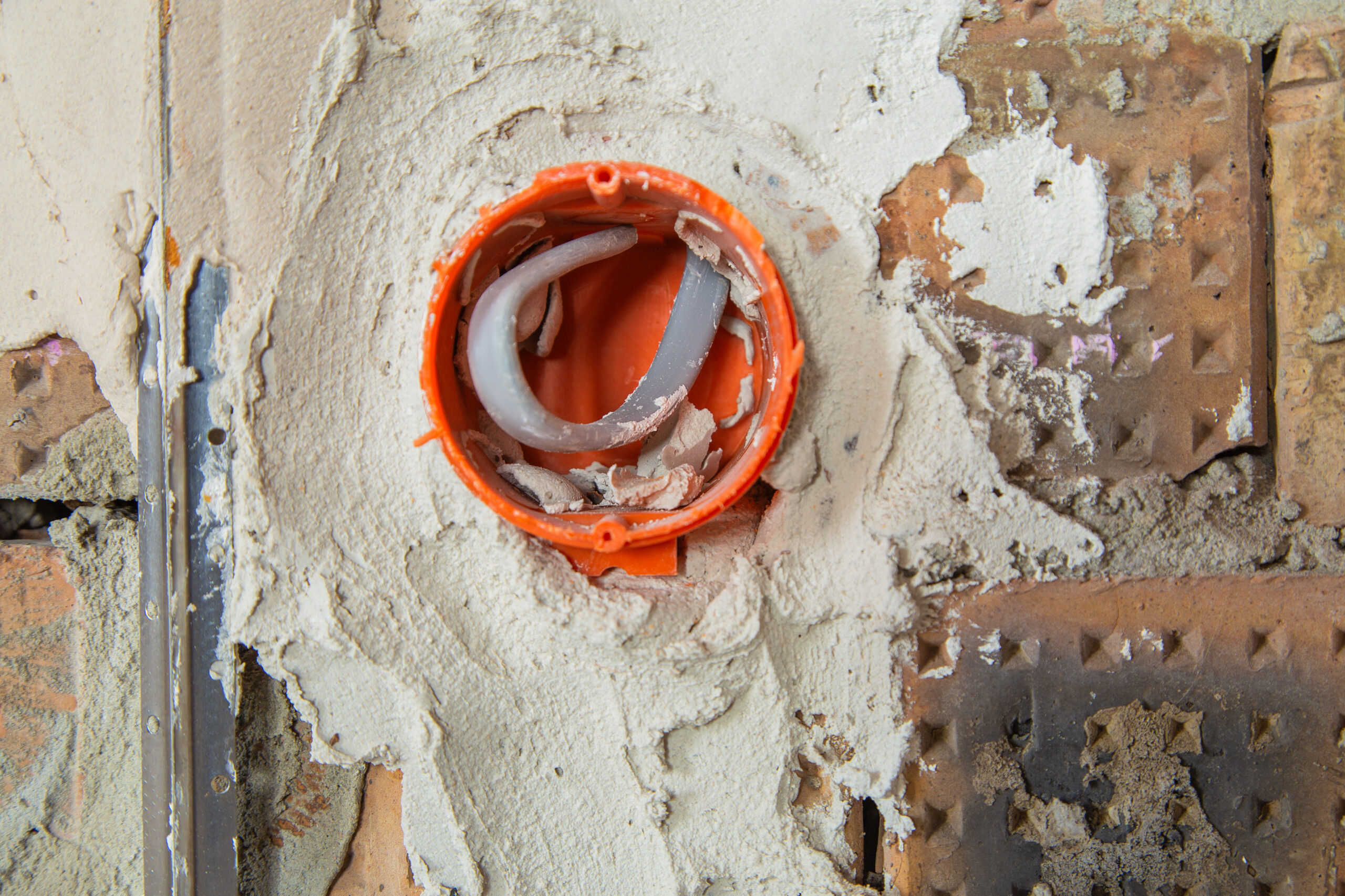 Socket orange boxes with wires in a wall. Cabling installation of electrical wires sticking out from electrical sockets hole on brick wall.