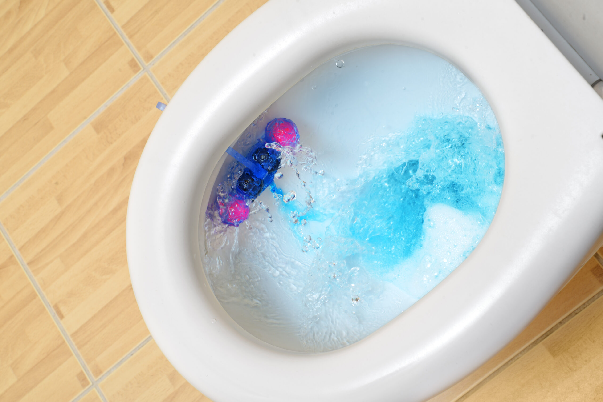 Toilet bowl with cleaner and freshener block, flushing blue water